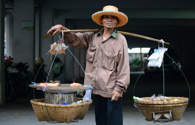 Man With Two Baskets Slung over Wooden Pole