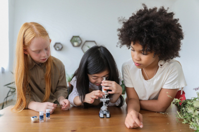 Focused little girls with microscope in room